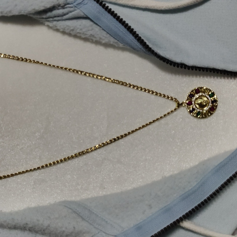 This necklace of the Virgin Mary is multi color and gold the chain is 23 inches